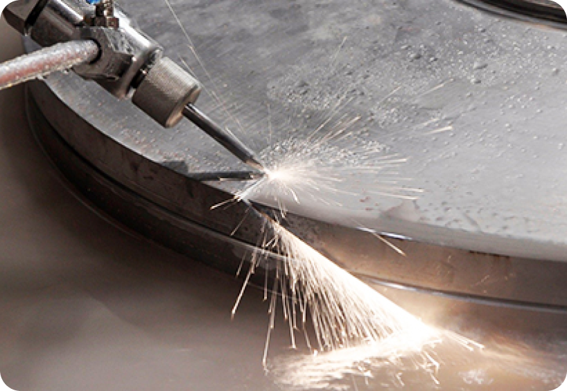 Close-up of waterjet cutting metal material, causing sparks. Flow has multi-axis cutting for production requirements.