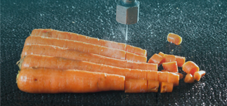 five carrots sitting on a waterjet brick being diced by a water only waterjet