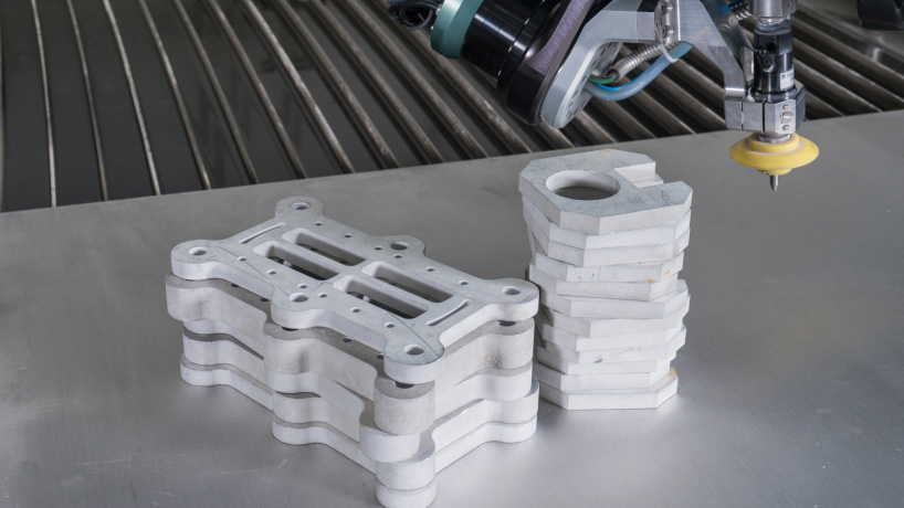 Stacks of thick cut metal pieces on a sheet of metal on waterjet table